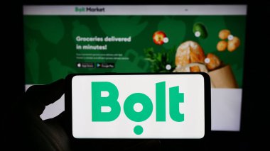 Stuttgart, Almanya - 07-26-2023: Web sayfasının önünde Estonya 'nın hareketlilik şirketi Bolt Technology' nin logosunun bulunduğu cep telefonu sahibi kişi. Telefon ekranına odaklan.