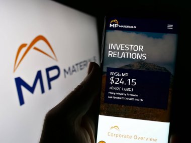 Stuttgart, Almanya - 07-27-2023: ABD 'li nadir bulunan dünya şirketleri milletvekili MP Material Corp' un web sayfasını elinde tutan kişi logonun önünde ekranda. Telefon ekranının merkezine odaklan.