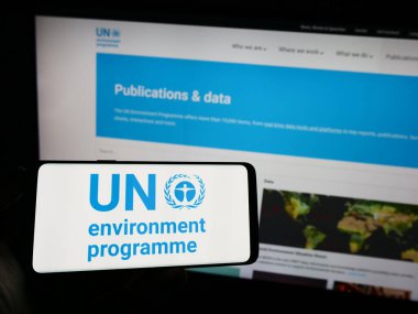 Stuttgart, Almanya - 07-27-2023: Birleşmiş Milletler Çevre Programı (UNEP) logosu olan cep telefonu sahibi kişi web sayfası önünde ekranda. Telefon ekranına odaklan.