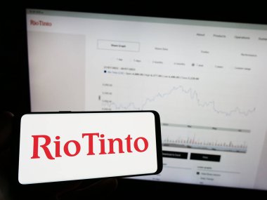 Stuttgart, Almanya - 07-27-2023: Madencilik şirketi Rio Tinto Group 'un logosuyla cep telefonu sahibi kişi iş sayfasının önünde ekranda. Telefon ekranına odaklan.