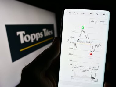 Stuttgart, Almanya - 07-27-2023: İngiliz perakende şirketi Topps Tiles plc 'in web sitesi ile cep telefonu tutan kişi logonun önünde ekranda. Telefon ekranının merkezine odaklan.