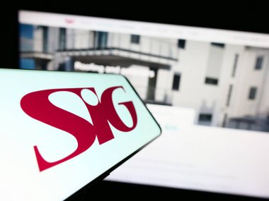 Stuttgart, Almanya - 07-27-2023: İngiliz inşaat malzemeleri şirketi SIG plc 'in logosunun yer aldığı cep telefonu iş sitesinin önünde ekranda. Telefon ekranının merkez soluna odaklan.