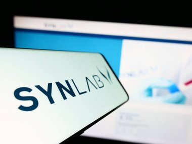 Stuttgart, Almanya - 07-27-2023: Ticari web sitesi önünde ekranda tıbbi teşhis şirketi SYNLAB Group 'un logosuna sahip akıllı telefon. Telefon ekranının merkez soluna odaklan.