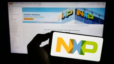 Stuttgart, Almanya - 07-28-2023: Hollandalı NXP Semiconductors N.V. şirketinin logosuna sahip akıllı telefon sahibi kişi web sitesinin önünde ekranda. Telefon ekranına odaklan.