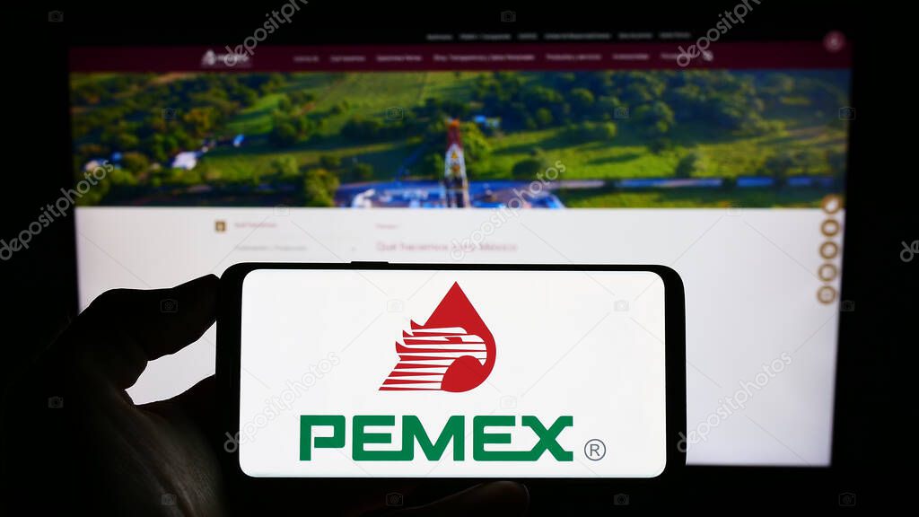 Stuttgart, Germany - 07-27-2023: Person holding cellphone with logo of oil company Petroleos Mexicanos (Pemex) on screen in front of business webpage. Focus on phone display.