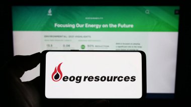 Stuttgart, Almanya - 07-28-2023: ABD 'li enerji şirketi EOG Resources Inc.' in logosuyla cep telefonu sahibi kişi iş sayfasının önünde ekranda. Telefon ekranına odaklan.