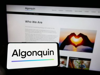 Stuttgart, Almanya - 07-28-2023: Kanadalı şirket Algonquin Power Utilities Corp 'un logosunu elinde tutan kişi web sitesinin önünde ekranda. Telefon ekranına odaklan.