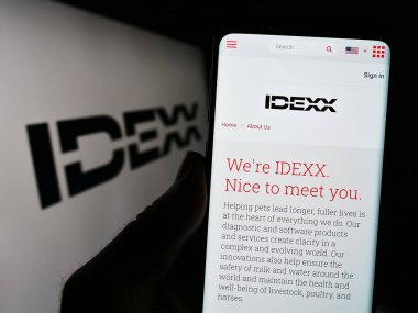 Stuttgart, Almanya - 07-29-2023: ABD 'li veteriner firması IDEXX Laboratories Inc.' in internet sayfası olan cep telefonu logolu kişi ekranda. Telefon ekranının merkezine odaklan.