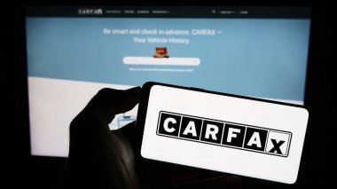 Stuttgart, Almanya - 07-29-2023: ABD 'li araç veri şirketi CARFAX Inc.' in logosuyla cep telefonu sahibi kişi iş sayfasının önünde ekranda. Telefon ekranına odaklan.