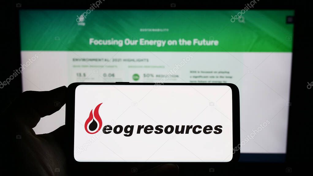 Stuttgart, Germany - 07-28-2023: Person holding cellphone with logo of US energy company EOG Resources Inc. on screen in front of business webpage. Focus on phone display.