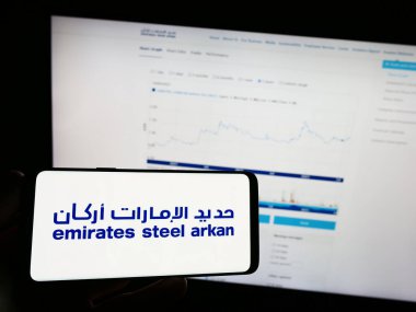 Stuttgart, Almanya - 07-30-2023: Emirates Steel Arkan (BAE) şirketinin logosuna sahip cep telefonu sahibi kişi iş sayfasının önünde ekranda görülüyor. Telefon ekranına odaklan.