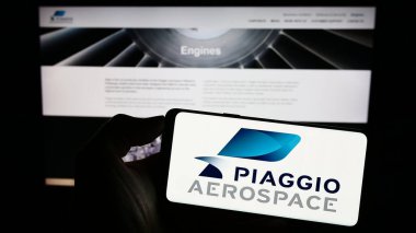 Stuttgart, Almanya - 07-30-2023: İtalyan Piaggio Aero Industries SpA şirketinin logosuyla cep telefonu sahibi kişi iş sayfasının önünde ekranda. Telefon ekranına odaklan.