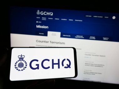 Stuttgart, Almanya - 07-30-2023: Devlet İletişim Merkezi (GCHQ) logosunun yer aldığı akıllı telefonu web sitesi önünde elinde tutan kişi. Telefon ekranına odaklan.