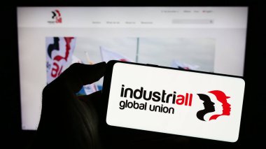 Stuttgart, Almanya - 07-31-2023: Endüstriyel Küresel Birlik organizasyonunun logosunun bulunduğu cep telefonu web sayfası önünde ekranda. Telefon ekranına odaklan.