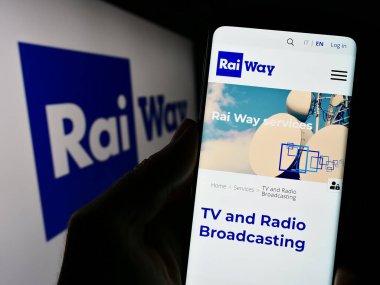 Stuttgart, Almanya - 08-01-2023: İtalyan altyapı şirketi Rai Way S.P.A. 'nın internet sayfası ile cep telefonu tutan kişi logolu ekranda. Telefon ekranının merkezine odaklan.