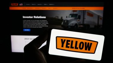 Stuttgart, Almanya - 08-01-2023: ABD 'li lojistik şirketi Yellow Corporation' ın logosuna sahip akıllı telefon sahibi kişi web sitesinin önünde ekranda. Telefon ekranına odaklan.