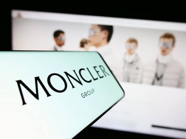 Stuttgart, Almanya - 08-02-2023: İtalyan moda şirketi Moncler S.P.A. 'nın logosunu taşıyan cep telefonu iş sitesinin önünde ekranda. Telefon ekranının merkez soluna odaklan.
