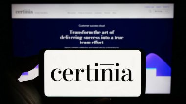 Stuttgart, Almanya - 08-02-2023: Amerikan yazılım şirketi Certinia Inc. 'in logosuyla cep telefonu sahibi kişi iş sayfasının önünde ekranda. Telefon ekranına odaklan.