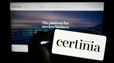 Stuttgart, Almanya - 08-02-2023: ABD 'li yazılım şirketi Certinia Inc.' in logosuyla cep telefonu sahibi kişi iş sayfasının önünde ekranda. Telefon ekranına odaklan.