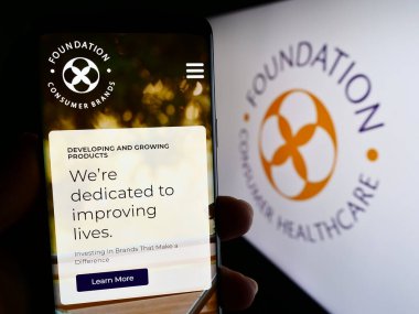 Stuttgart, Almanya - 08-02-2023: ABD 'li şirket Vakfı Tüketici Sağlık LLLC' nin web sayfası ile cep telefonu tutan kişi logo ile ekranda. Telefon ekranının merkezine odaklan.