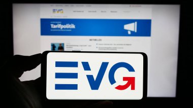 Stuttgart, Germany - 08-02-2023: Person holding cellphone with logo of union Eisenbahn- und Verkehrsgewerkschaft (EVG) on screen in front of webpage. Focus on phone display. clipart