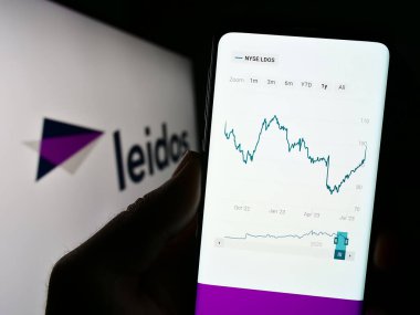 Stuttgart, Almanya - 08-02-2023: ABD 'li savunma şirketi Leidos Inc.' in web sitesi ile cep telefonu sahibi kişi iş logosu önünde ekranda. Telefon ekranının sol üst kısmına odaklan.