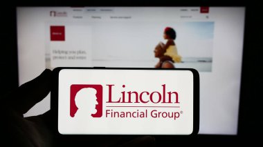 Stuttgart, Almanya - 08-02-2023: ABD 'li finans şirketi Lincoln National Corporation' ın logosunu elinde tutan kişi web sitesinin önünde ekranda. Telefon ekranına odaklan.