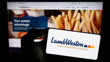 Stuttgart, Almanya - 08-02-2023: ABD 'li patates şirketi Lamb Weston Holding Inc.' in logosuyla cep telefonu sahibi kişi iş sayfasının önünde ekranda. Telefon ekranına odaklan.