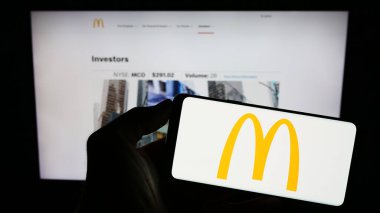 Stuttgart, Almanya - 08-04-2023: ABD 'li fast food şirketi McDonald' s Corporation 'ın logosunu taşıyan kişi web sitesinin önünde ekranda. Telefon ekranına odaklan.