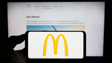 Stuttgart, Almanya - 08-04-2023: Amerikan fast food şirketi McDonald 's Corporation' ın logosunun bulunduğu cep telefonu web sayfasının önünde ekranda. Telefon ekranına odaklan.