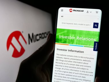 Stuttgart, Almanya - 08-04-2023: Yarı iletken firma Microchip Technology Inc. 'in web sitesi ile cep telefonu tutan kişi logolu ekranda. Telefon ekranının merkezine odaklan.
