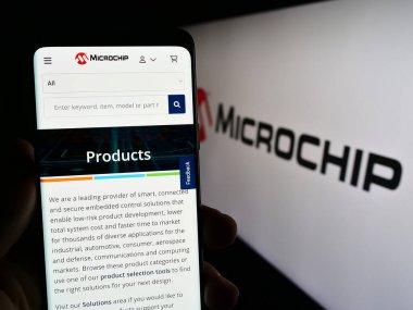 Stuttgart, Almanya - 08-04-2023: Yarı iletken şirket Microchip Technology Inc. 'in web sayfası ile cep telefonu tutan kişi logolu ekranda. Telefon ekranının merkezine odaklan.