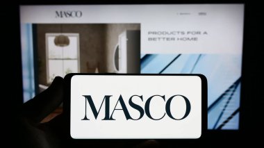 Stuttgart, Almanya - 08-04-2023: Sitenin önünde ekranda ABD 'li ev geliştirme şirketi Masco Corporation' ın logosunu taşıyan kişi. Telefon ekranına odaklan.