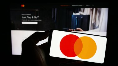 Stuttgart, Almanya - 08-04-2023: ABD 'li ödeme şirketi Mastercard Inc.' nin logosuyla cep telefonu sahibi kişi iş sayfasının önünde ekranda. Telefon ekranına odaklan.