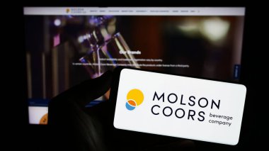 Stuttgart, Almanya - 08-05-2023: İnternet sitesinin önünde Molson Coors Beverage Company 'nin logosunun bulunduğu akıllı telefonu elinde tutan kişi. Telefon ekranına odaklan.