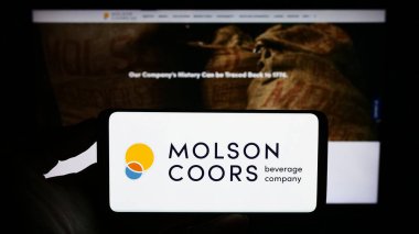 Stuttgart, Almanya - 08-05-2023: İş yeri logosu Molson Coors Beverage Company 'nin cep telefonu sahibi kişi iş sayfasının önünde ekranda. Telefon ekranına odaklan.