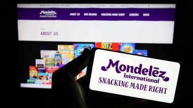 Stuttgart, Almanya - 08-05-2023: Web sitesi önünde ekranda ABD 'li gıda şirketi Mondelez International Inc.' in logosunu taşıyan kişi. Telefon ekranına odaklan.