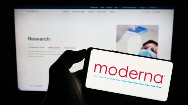 Stuttgart, Almanya - 08-05-2023: ABD 'li ilaç şirketi Moderna Inc.' in logosuyla cep telefonu sahibi kişi iş sayfasının önünde ekranda. Telefon ekranına odaklan.