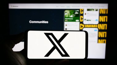 Stuttgart, Almanya - 08-05-2023: ABD 'li sosyal medya şirketi X Corp' un logosunun bulunduğu cep telefonu sahibi kişi iş sayfası önünde ekranda. Telefon ekranına odaklan.