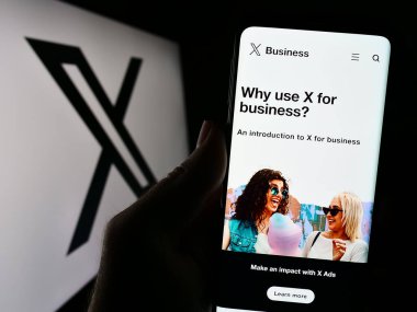 Stuttgart, Almanya - 08-05-2023: ABD 'li sosyal medya şirketi X Corp.' un (Twitter) internet sitesi olan cep telefonu logosu önünde ekranda. Telefon ekranının merkezine odaklan.