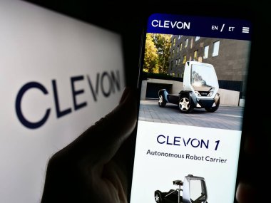 Stuttgart, Almanya - 08-05-2023: Estiyonyalı otonom araç şirketi Clevon AS 'in web sayfası ile birlikte cep telefonu tutan kişi logolu ekranda. Telefon ekranının merkezine odaklan.