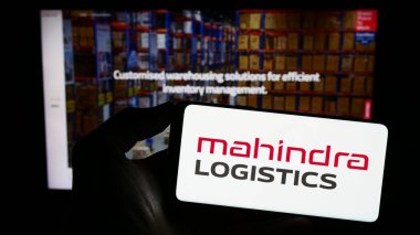 Stuttgart, Almanya - 08-05-2023: Hint Mahindra Lojistik Ltd. 'nin logosu olan cep telefonu sahibi kişi iş sayfasının önünde ekranda. Telefon ekranına odaklan.