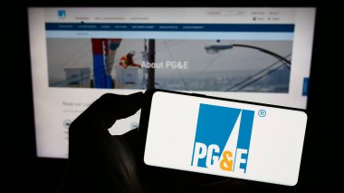 Stuttgart, Almanya - 08-05-2023: İnternet sitesi önünde Pacific Gas ve Electric Company 'nin (PGE) logosuna sahip akıllı telefonu elinde tutan kişi. Telefon ekranına odaklan.