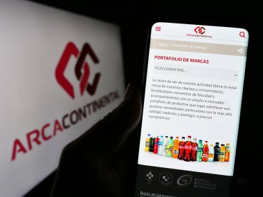 Stuttgart, Almanya - 08-05-2023: Arca Continental S.A.B. şirketinin web sayfası ile cep telefonu tutan kişi De CV ekranda logonun önünde. Telefon ekranının merkezine odaklan.