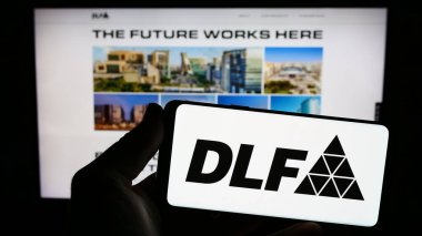 Stuttgart, Almanya - 08-06-2023: Hintli emlak şirketi DLF Limited 'in logosuna sahip akıllı telefon sahibi kişi web sitesinin önünde ekranda. Telefon ekranına odaklan.