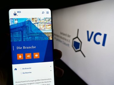 Stuttgart, Almanya - 08-06-2023: Verband der Chemischen Industrie web sitesi ile cep telefonu tutan kişi. Logonun önündeki ekranda (VCI). Telefon ekranının merkezine odaklan.