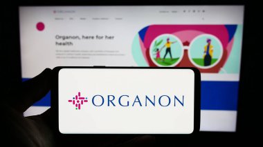 Stuttgart, Almanya - 08-06-2023: Web sitesi önünde ekranda ABD 'li ilaç şirketi Organon Co.' nun logosunu taşıyan kişi. Telefon ekranına odaklan.