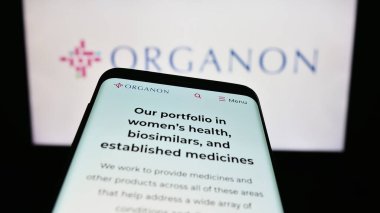 Stuttgart, Germany - 08-06-2023: Smartphone with website of US pharmaceutical company Organon Co. on screen in front of business logo. Focus on top-left of phone display. clipart