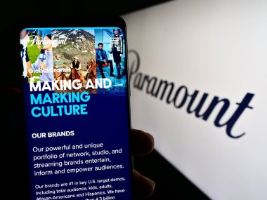 Stuttgart, Almanya - 08-06-2023: ABD 'li eğlence şirketi Paramount Global' ın web sayfası ile birlikte logo önünde cep telefonu tutan kişi. Telefon ekranının merkezine odaklan.