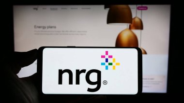 Stuttgart, Almanya - 08-06-2023: ABD 'li kamu hizmeti şirketi NRG Energy Inc.' in logosuyla cep telefonu sahibi kişi iş sayfasının önünde ekranda. Telefon ekranına odaklan.